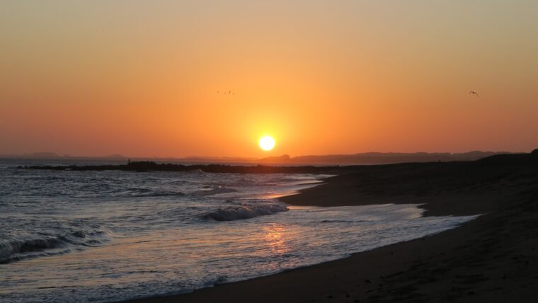 sea waves crashing on shore during sunset